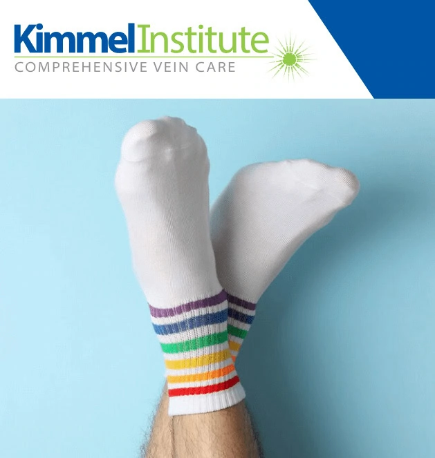 Feet in white socks with rainbow stripes raised, Boca Raton vein treatment center logo above.