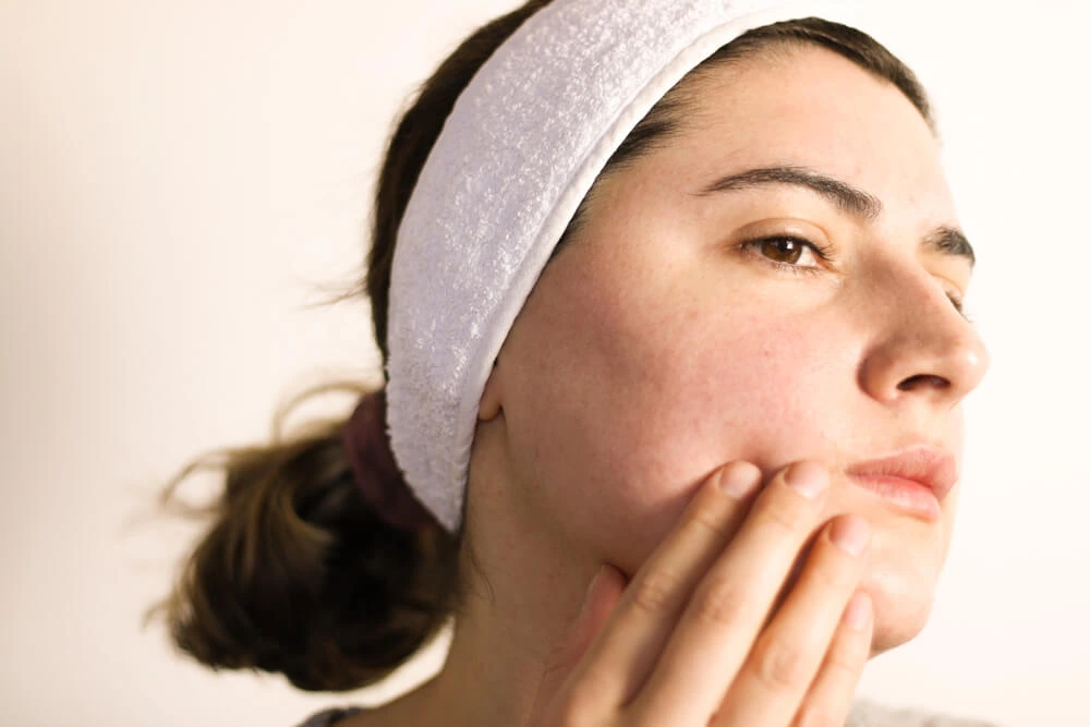 A woman with rosacea and chin veins looking in the mirror