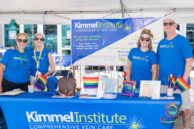 Four staff in Vein Treatment Center shirts at Boca Raton event booth on vein health.