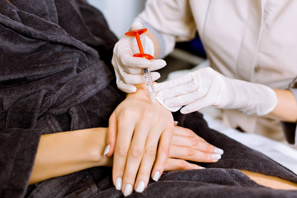 A doctor performing a sclerotherapy injection for varicose veins in the hands