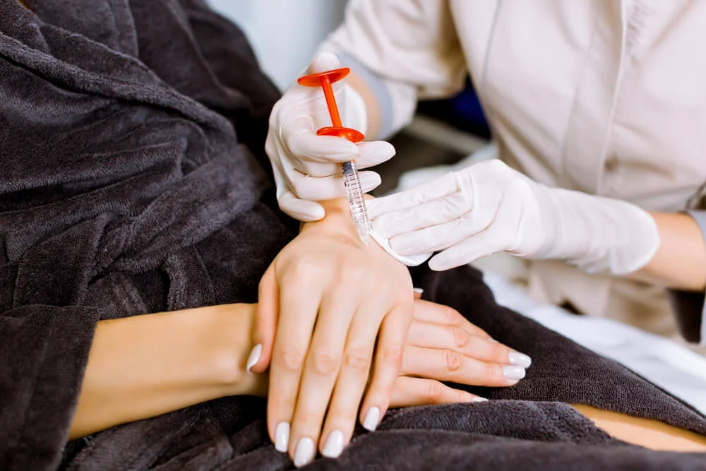 A doctor performing a sclerotherapy injection for varicose veins in the hands