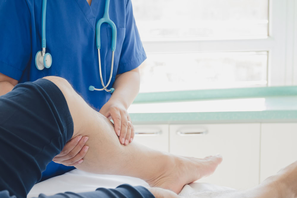 A Boca Raton vein specialist examines a patient’s leg for vein disease symptoms.