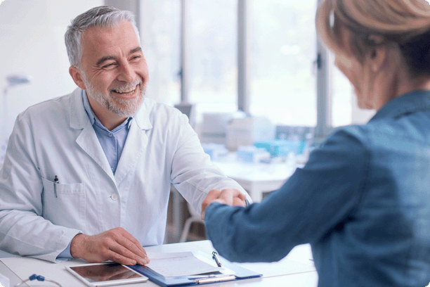 older male doctor is shaking hands with middle-aged woman