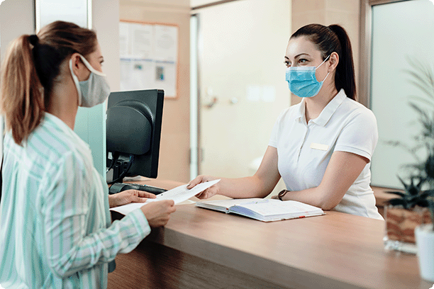 female receptionist helping female patient with paperwork