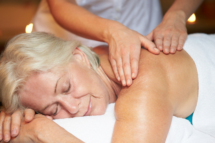 Smiling senior woman receiving a massage at the spa
